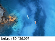 Aerial view of people on floating kayaks on blue sea, rocky coast, trees at sunrise in summer. Blue lagoon, Oludeniz, Turkey. Tropical landscape. Sup boards on clear water. Top view of canoe. Tourism. Стоковое фото, агентство Ingram Publishing / Фотобанк Лори