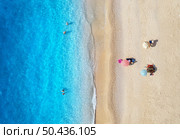 Aerial view of adriatic sea, waves, sandy beach and umbrellas with lying people at sunset in summer. Tropical landscape with clear turquoise water. Top view from drone. Lefkada island, Greece. Travel. Стоковое фото, агентство Ingram Publishing / Фотобанк Лори