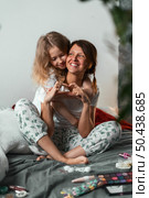 Smiling mother and daughter enjoy funny makeup moment together, showing unconditional love, emotional closeness in safe, familiar home space. Make heart with your fingers hands. Стоковое фото, фотограф Енваев Андрей / Фотобанк Лори