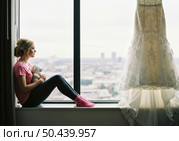 Последние минуты девичества: задумчивая невеста с игрушкой перед свадебным платьем. Стоковое AI-изображение, AI-художник Сергей Никифоров-Гордеев / Фотобанк Лори