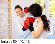 Focused woman practicing boxing punches in sparring during group self defence course. Стоковое фото, фотограф Яков Филимонов / Фотобанк Лори
