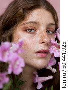 portrait freckled woman holding pink flower. Стоковое фото, агентство Ingram Publishing / Фотобанк Лори
