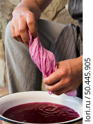 man squeezing cloth from pink natural pigment. Стоковое фото, агентство Ingram Publishing / Фотобанк Лори