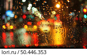 A street in the city is seen through a rain-covered window, with droplets distorting the view of cars, buildings, and pedestrians. Стоковое AI-изображение, AI-художник Данила Большаков / Фотобанк Лори