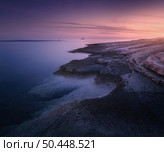 Rocky sea coast and lighthouse at colorful sunset in summer. Beautiful landscape with beach, stones in blurred blue water, purple sky at dusk. Nature. Adriatic sea at night, Kamenjak, Croatia. Travel. Стоковое фото, агентство Ingram Publishing / Фотобанк Лори