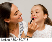 Mother playing with her daughter applying lipstick. Стоковое фото, агентство Ingram Publishing / Фотобанк Лори