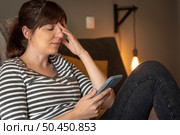 Woman on bed at phone with symptoms of depression. Стоковое фото, агентство Ingram Publishing / Фотобанк Лори