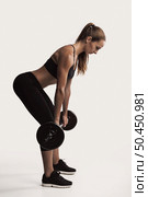 Shot of a beautiful young woman in a workout gear lifting weights. Стоковое фото, агентство Ingram Publishing / Фотобанк Лори