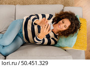 Top view of a beautiful woman on the sofa sending a text message. Стоковое фото, агентство Ingram Publishing / Фотобанк Лори
