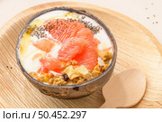 Yogurt with grapefruit, granola, chia and honey served in half a coconut shell on a rose marble kitchen countertop. Стоковое фото, агентство Ingram Publishing / Фотобанк Лори