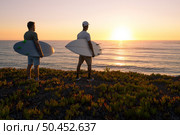 Surfers watching the waves at sunset on top of a sand dune in Maceda, Ovar -  Portugal. Стоковое фото, агентство Ingram Publishing / Фотобанк Лори