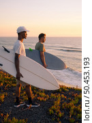 Surfers watching the waves at sunset on top of a sand dune in Maceda, Ovar -  Portugal. Стоковое фото, агентство Ingram Publishing / Фотобанк Лори