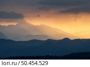 Amazing silhouettes of a mountains at colorful sunset in summer in Slovenia. Landscape with mountain ridges in fog, golden sunlight and clouds in the evening. Nature. Hills in sunlight. Scenery. Стоковое фото, агентство Ingram Publishing / Фотобанк Лори
