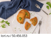 Meat patties and parsley leaves on white ceramic dishes in a kitchen counter top. Стоковое фото, агентство Ingram Publishing / Фотобанк Лори