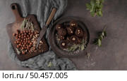 Dark chocolate truffles with hazelnuts and chopped hazelnuts over wooden cutting board. Стоковое фото, агентство Ingram Publishing / Фотобанк Лори
