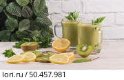 Glasses of green vegetable smoothie. Green vegetable smoothie and ingredients: Kiwi, lemon and herbs. Стоковое фото, агентство Ingram Publishing / Фотобанк Лори