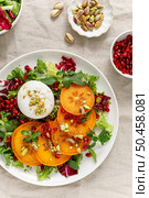 Salad with persimmon, burrata, pomegranate and pistachio, healthy food, top view. Стоковое фото, агентство Ingram Publishing / Фотобанк Лори