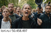 A passionate woman leads a group of protesters, loudly voicing demands with a megaphone as they march together for a cause. Стоковое AI-изображение, AI-художник Данила Большаков / Фотобанк Лори