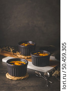 Creme brulee. Bowls with French vanilla cream dessert with caramelised sugar on top, spoons, dark rustic table. Стоковое фото, агентство Ingram Publishing / Фотобанк Лори