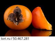 Persimmon fruits on black background. Стоковое фото, агентство Ingram Publishing / Фотобанк Лори