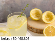 Cold lemonade or alcoholic cocktail with lemon, rosemary and ice in glass glasses on a light background. Стоковое фото, агентство Ingram Publishing / Фотобанк Лори