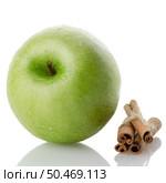 Ripe green apple with cinnamon sticks over reflective white background. Стоковое фото, агентство Ingram Publishing / Фотобанк Лори