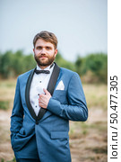 Handsome groom in wedding suit posting in the park. Стоковое фото, агентство Ingram Publishing / Фотобанк Лори
