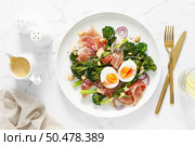Easter egg salad with prosciutto and broccolini on white background, top view. Easter salad with boiled egg. Стоковое фото, агентство Ingram Publishing / Фотобанк Лори