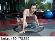 Young women warms up before exercising by pushing the floor and bending his knees in Gym. Стоковое фото, агентство Ingram Publishing / Фотобанк Лори