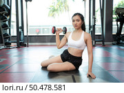 Woman sit exercising with a dumbbell in the gym. Стоковое фото, агентство Ingram Publishing / Фотобанк Лори