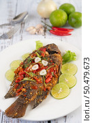 Fried tilapia with chili sauce, lemon salad and garlic on a plate on a white wooden table. Стоковое фото, агентство Ingram Publishing / Фотобанк Лори