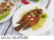 Fried tilapia with chili sauce, lemon salad and garlic on a plate on a white wooden table. Стоковое фото, агентство Ingram Publishing / Фотобанк Лори