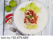 Spicy lemon squid with galangal, chilies, carrots, peppermint, spring onions and garlic on a plate on a white wooden floor. Стоковое фото, агентство Ingram Publishing / Фотобанк Лори