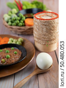 Chili paste paste in a bowl with eggplant, carrots, chili, cucumbers in a basket on wood table. Стоковое фото, агентство Ingram Publishing / Фотобанк Лори
