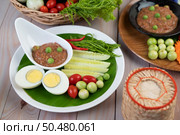 Chili paste paste in a bowl with eggplant, carrots, chili, cucumbers in a basket on wood table. Стоковое фото, агентство Ingram Publishing / Фотобанк Лори