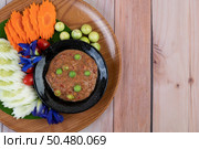 Chili paste paste in a bowl with eggplant, carrots, chili, cucumbers in a basket on wood table. Стоковое фото, агентство Ingram Publishing / Фотобанк Лори