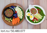 Chili paste paste in a bowl with eggplant, carrots, chili, cucumbers in a basket on wood table. Стоковое фото, агентство Ingram Publishing / Фотобанк Лори