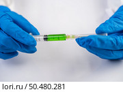 Scientists wearing masks and gloves Holding a syringe with a vaccine to prevent covic-19. Стоковое фото, агентство Ingram Publishing / Фотобанк Лори