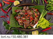 Stir-fried chicken liver basil on banana leaves in a black dish. Thai food. Стоковое фото, агентство Ingram Publishing / Фотобанк Лори