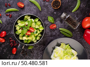 Cucumber stir-fried with tomatoes and red beans in a frying pan with green peas Pepper seeds on black cement. Стоковое фото, агентство Ingram Publishing / Фотобанк Лори