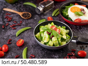 Cucumber stir-fried with tomatoes and red beans in a frying pan with green peas Pepper seeds on black cement. Стоковое фото, агентство Ingram Publishing / Фотобанк Лори