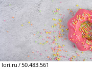 Half a strawberry donut decorated icing and sprinkling on the floor. Стоковое фото, агентство Ingram Publishing / Фотобанк Лори