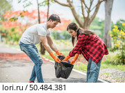 Men and women helped to collect garbage in a black bag. Стоковое фото, агентство Ingram Publishing / Фотобанк Лори