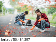 Men and women helped to collect garbage in a black bag. Стоковое фото, агентство Ingram Publishing / Фотобанк Лори