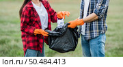 Men and women helped to collect garbage in a black bag. Стоковое фото, агентство Ingram Publishing / Фотобанк Лори