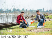 Men and women helped to collect garbage in a black bag. Стоковое фото, агентство Ingram Publishing / Фотобанк Лори