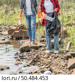 Men and women helped to collect garbage in a black bag. Стоковое фото, агентство Ingram Publishing / Фотобанк Лори