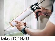 The carpenter holds the glue and attaches to the window. Selective focus. Стоковое фото, агентство Ingram Publishing / Фотобанк Лори
