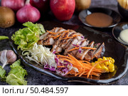 Sliced ??pork steak with bread, carrots, cauliflower, lettuce and corn on a black plate on a cement floor. Стоковое фото, агентство Ingram Publishing / Фотобанк Лори