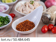 Cayenne chili in a white spoon, tomato placed on a wooden table. Selective focus. Стоковое фото, агентство Ingram Publishing / Фотобанк Лори